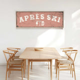 a wooden dining table with four chairs, and a framed sign above it that reads "APRés Ski".