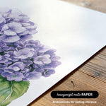 a close-up view of a piece of paper with a detailed illustration of a cluster of purple hydrangea flowers.