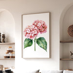 a framed painting of a pink hydrangea flower hanging on a wall in a living room.