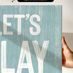 a hand holding a sign that says let&#39;s play
