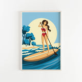 A woman in a red swimsuit is paddleboarding on a blue ocean, holding a paddle and standing on a surfboard.