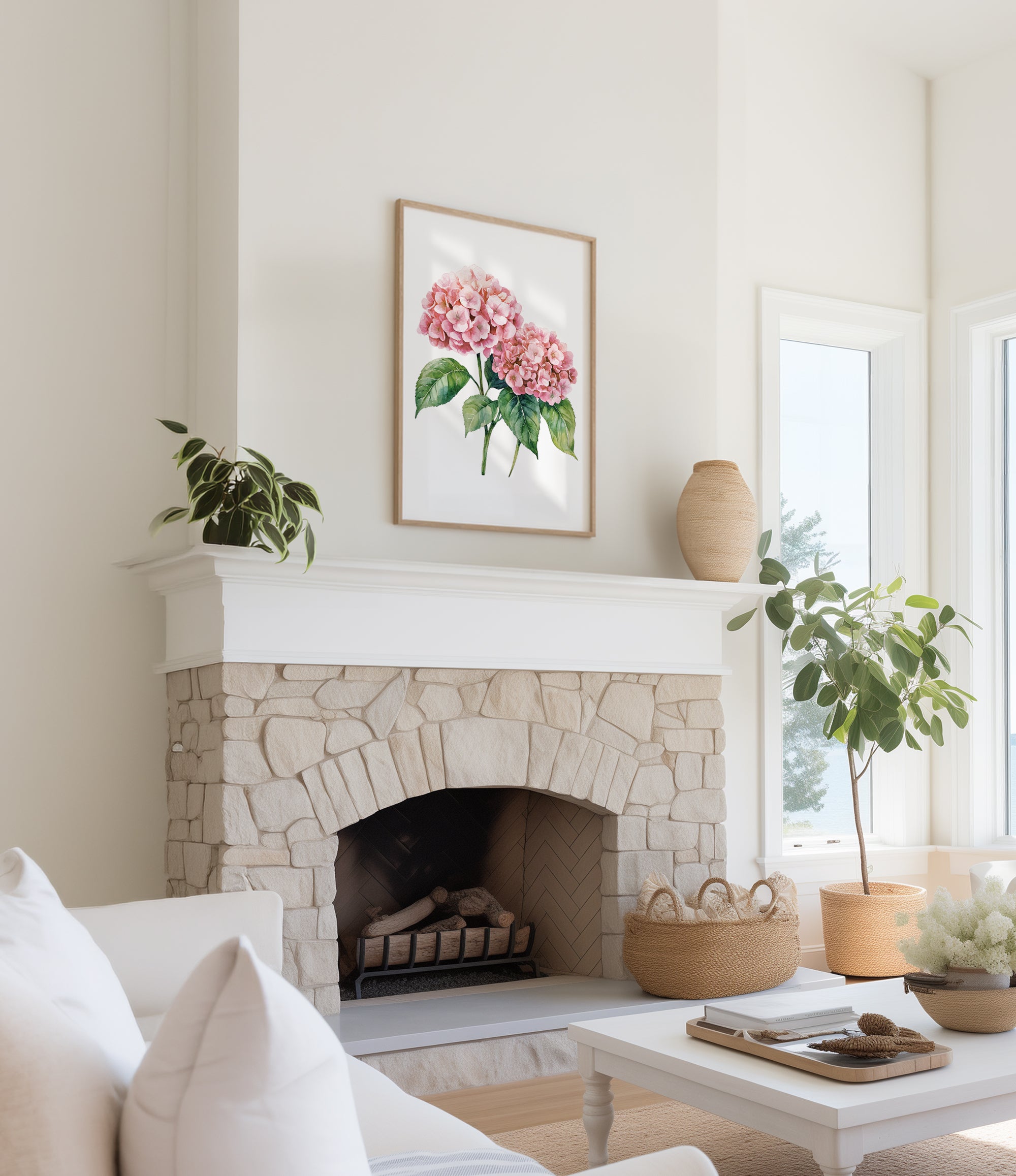 a cozy living room with a stone fireplace, a framed watercolor painting of pink hydrangeas hanging above it, and a white sofa. The room is decorated with potted plants and a woven basket, creating a warm and inviting atmosphere.