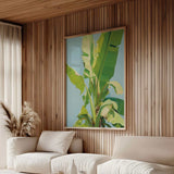 a modern living room with a large, vibrant painting of a banana tree hanging on the wall. The room is furnished with two white sofas and a coffee table, creating a cozy and inviting atmosphere.