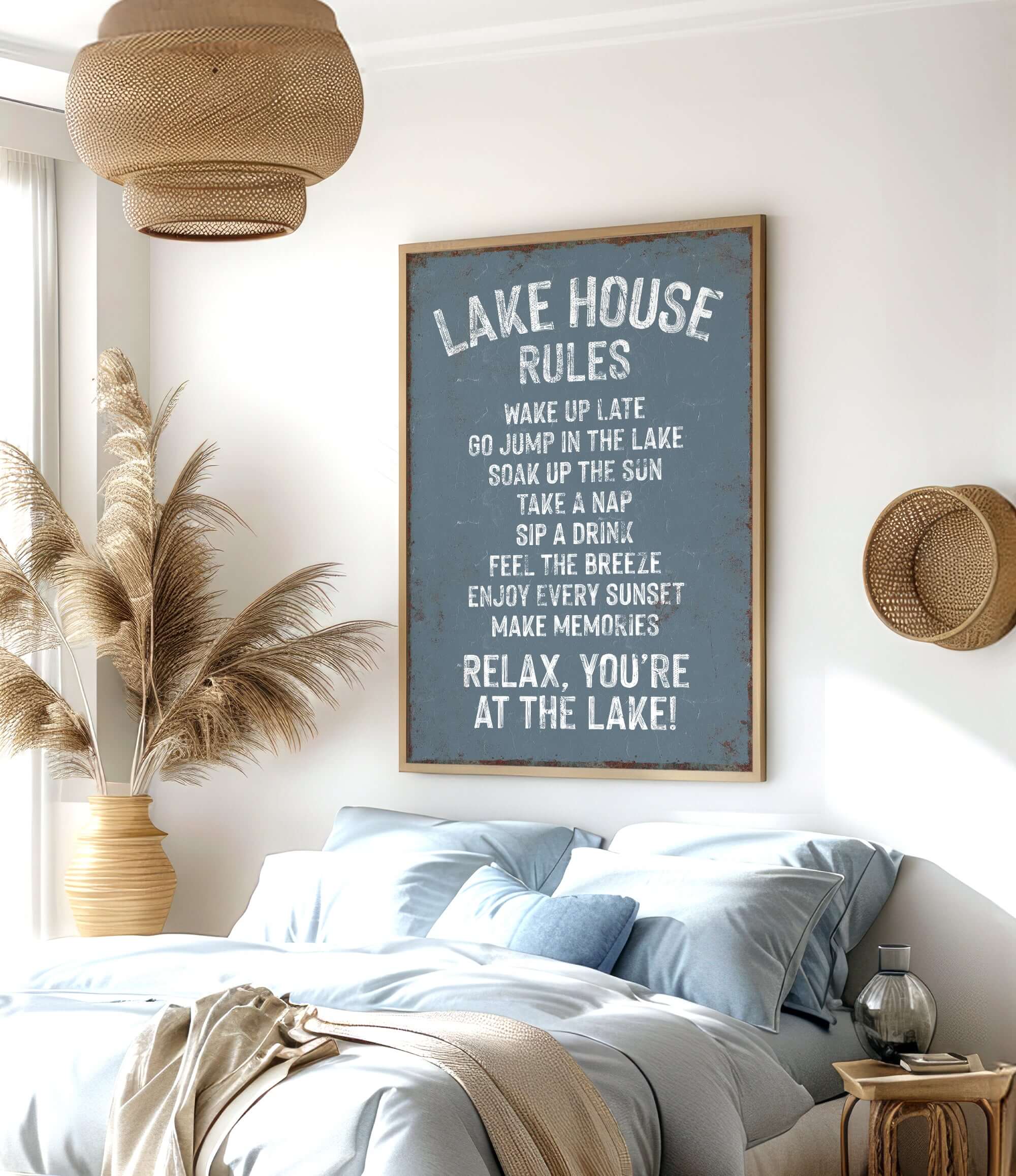 a bedroom with a large sign that reads "LAKESHORE RULES" hanging on the wall. The sign provides a list of rules for guests at the lake, including instructions to wake up late, go for a swim, take a nap, drink a beverage, enjoy the breeze, and relax. The room has a comfortable bed, a potted plant, and a woven basket on the wall, creating a cozy and inviting atmosphere.