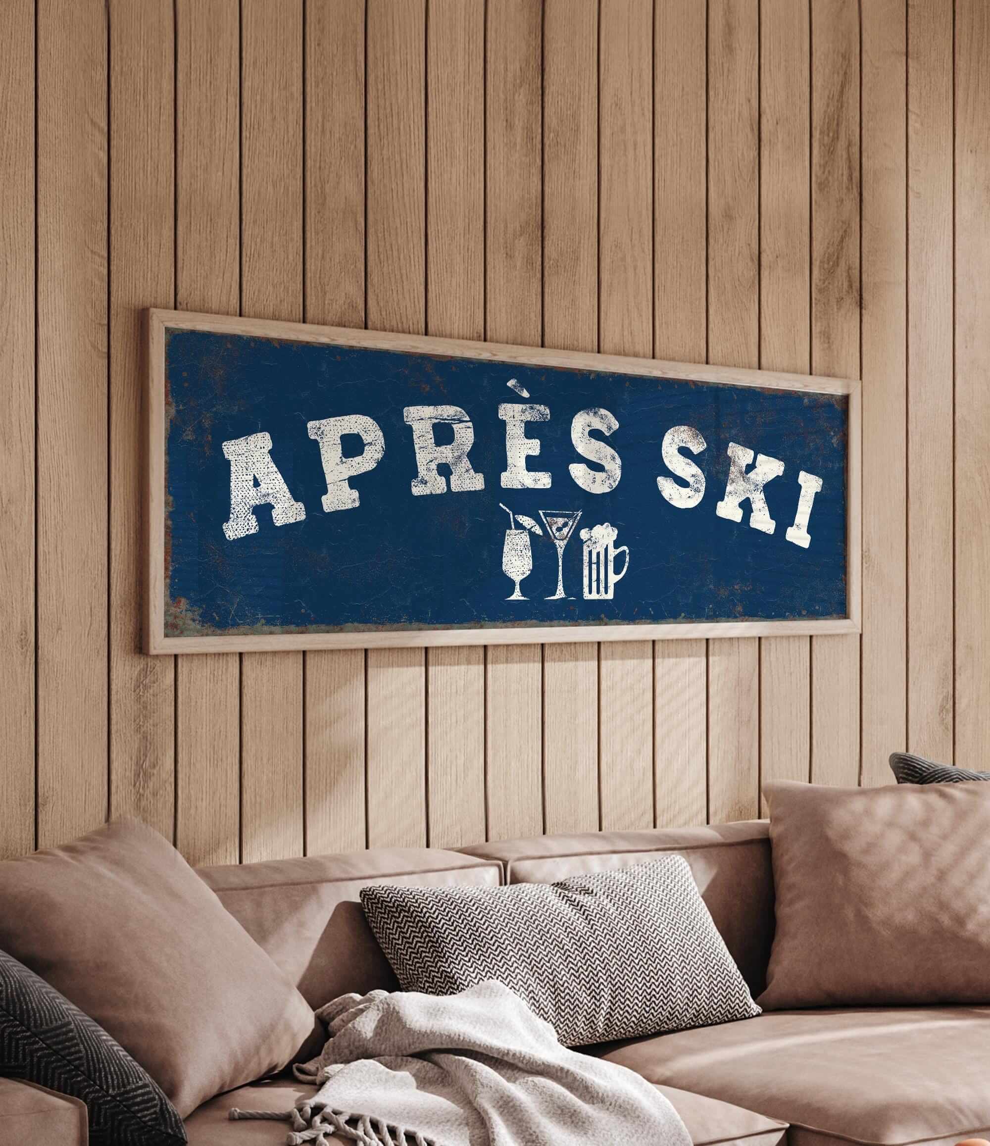 a blue sign with white text that says "APRÈS SKI" hanging on a wooden wall above a couch with pillows.