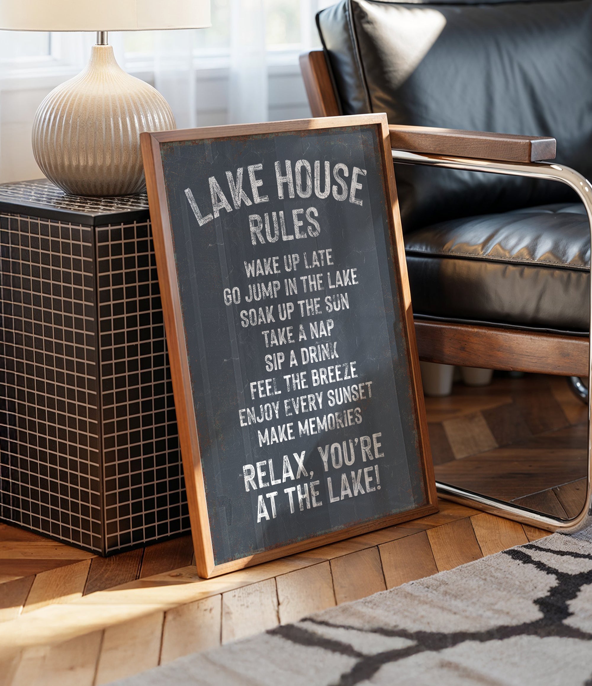 A chalkboard sign with the text "LAKE HOUSE RULES" written on it, placed on a wooden floor next to a chair.