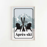 A framed print featuring a pair of black Adirondack chairs with skis crossed in front of them, set against a snowy mountain landscape.