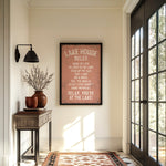 a hallway with a framed sign that reads "LAKESHORE RULES" hanging on the wall. The hallway has a wooden table with a vase of flowers, a rug, and a large window with a view of trees outside.