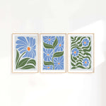 three paintings of blue flowers on a white wall