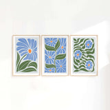 three paintings of blue flowers on a white wall