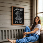 A woman is sitting on a bench in front of a sign that provides rules for the lake house.