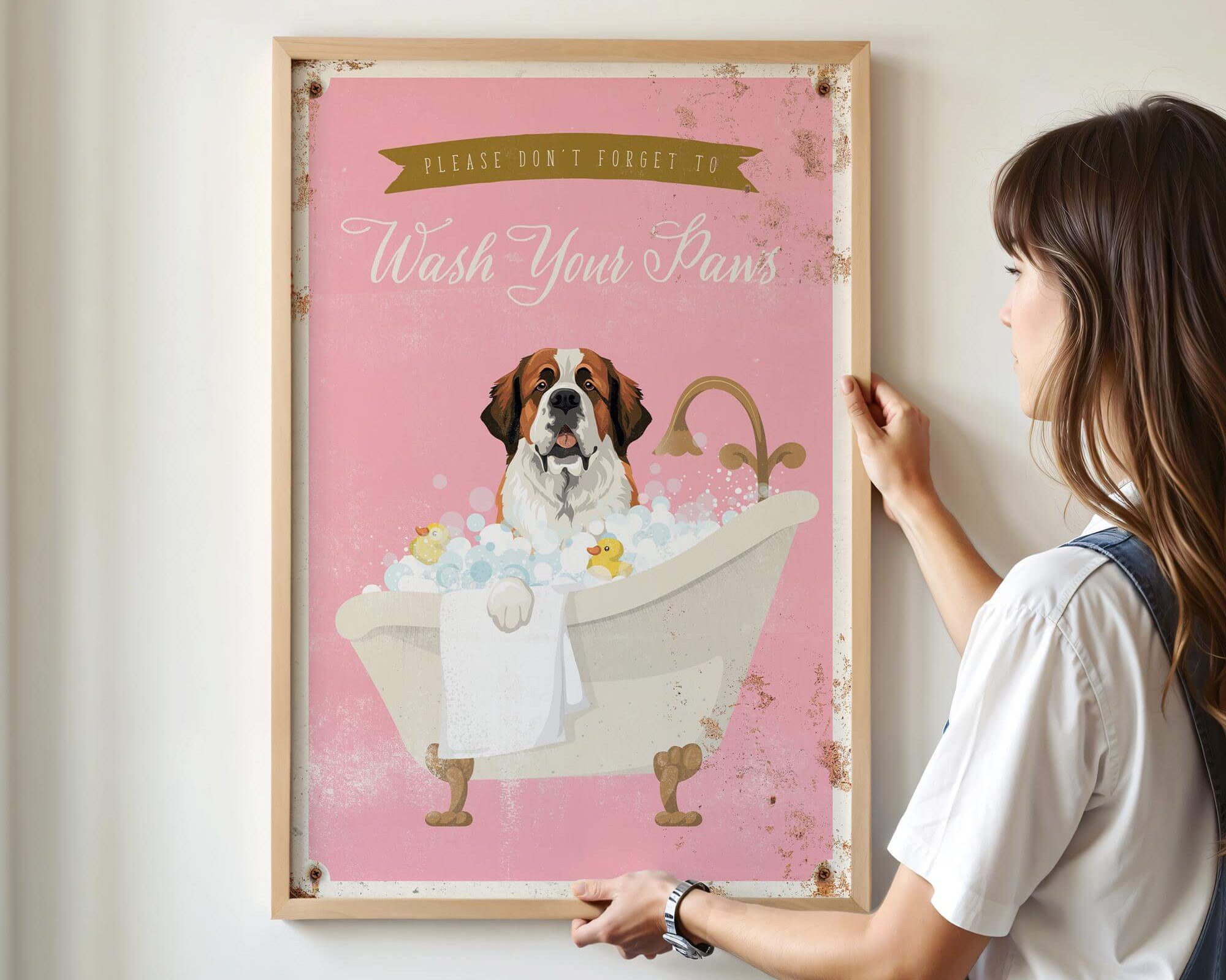 A woman is hanging a framed poster on a wall that features a dog sitting in a bathtub filled with bubbles.