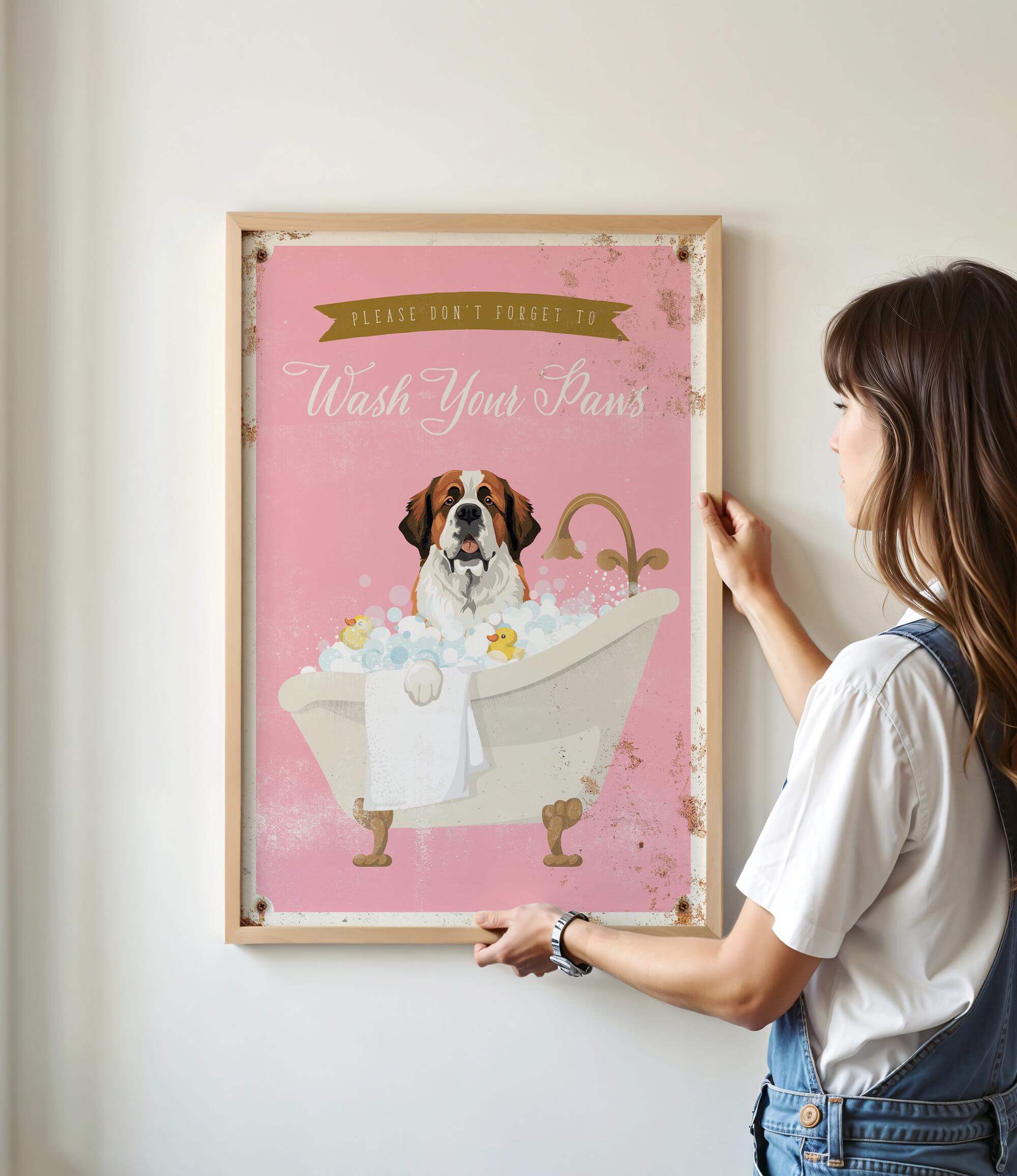 A woman is hanging a framed poster on a wall that features a dog sitting in a bathtub filled with bubbles.