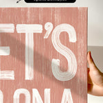 a person holding up a pink poster with white lettering