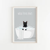 A framed poster with a black cat sitting in a white bathtub filled with bubbles, with the text "WASH YOUR PAWS" displayed above the cat.