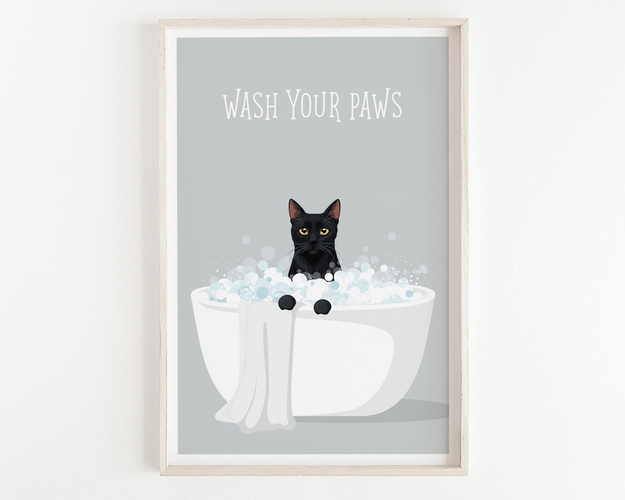 A framed poster with a black cat sitting in a white bathtub filled with bubbles, with the text "WASH YOUR PAWS" displayed above the cat.