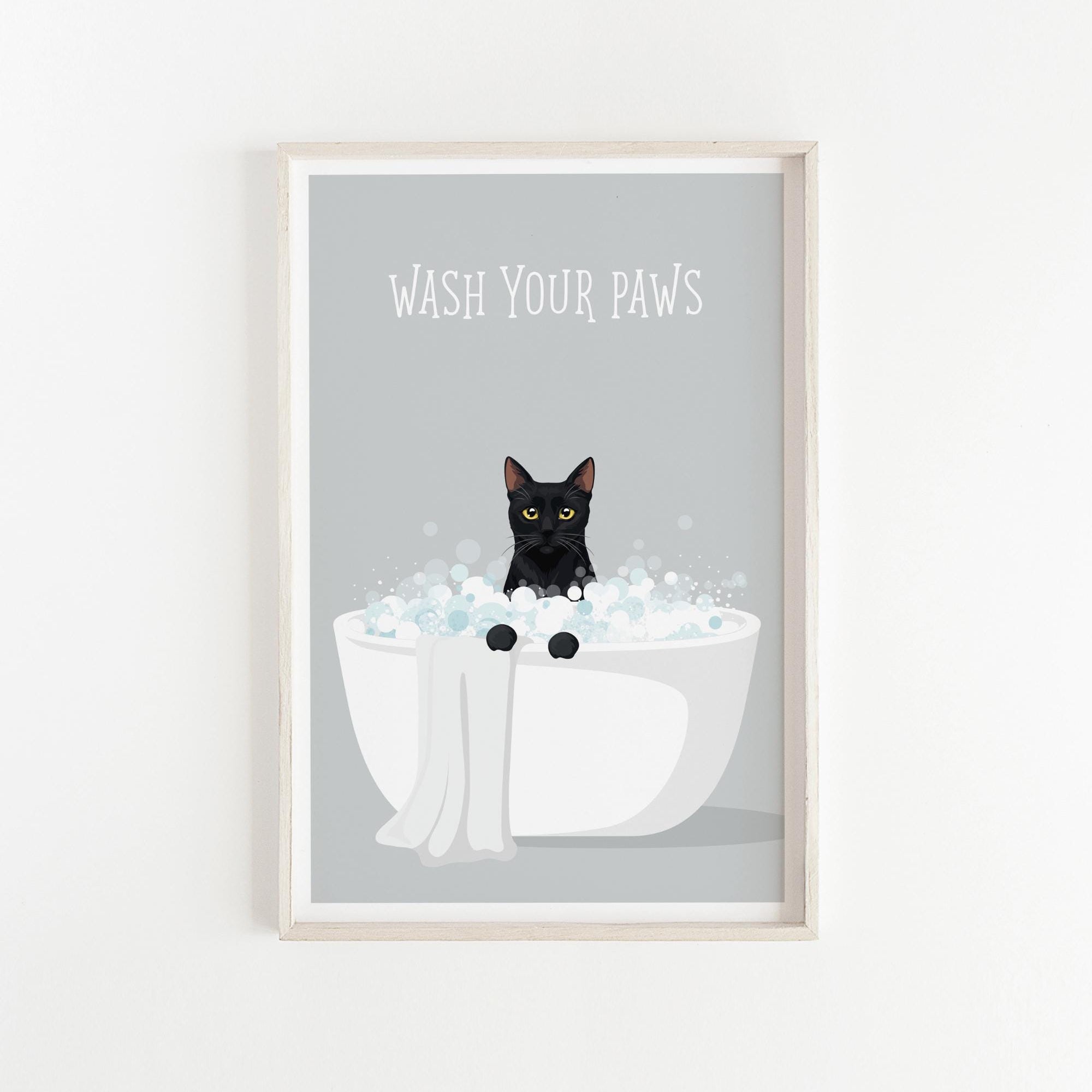 A framed poster with a black cat sitting in a white bathtub filled with bubbles, with the text "WASH YOUR PAWS" displayed above the cat.