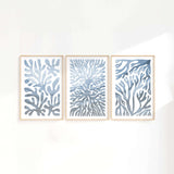 three paintings of blue corals on a white wall