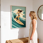 A woman in a white dress stands in a room, looking at a framed illustration of a woman surfing on a wave.