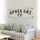 a living room with a striped couch, a coffee table, and a large sign that says "APRÈS SKI" hanging on the wall.