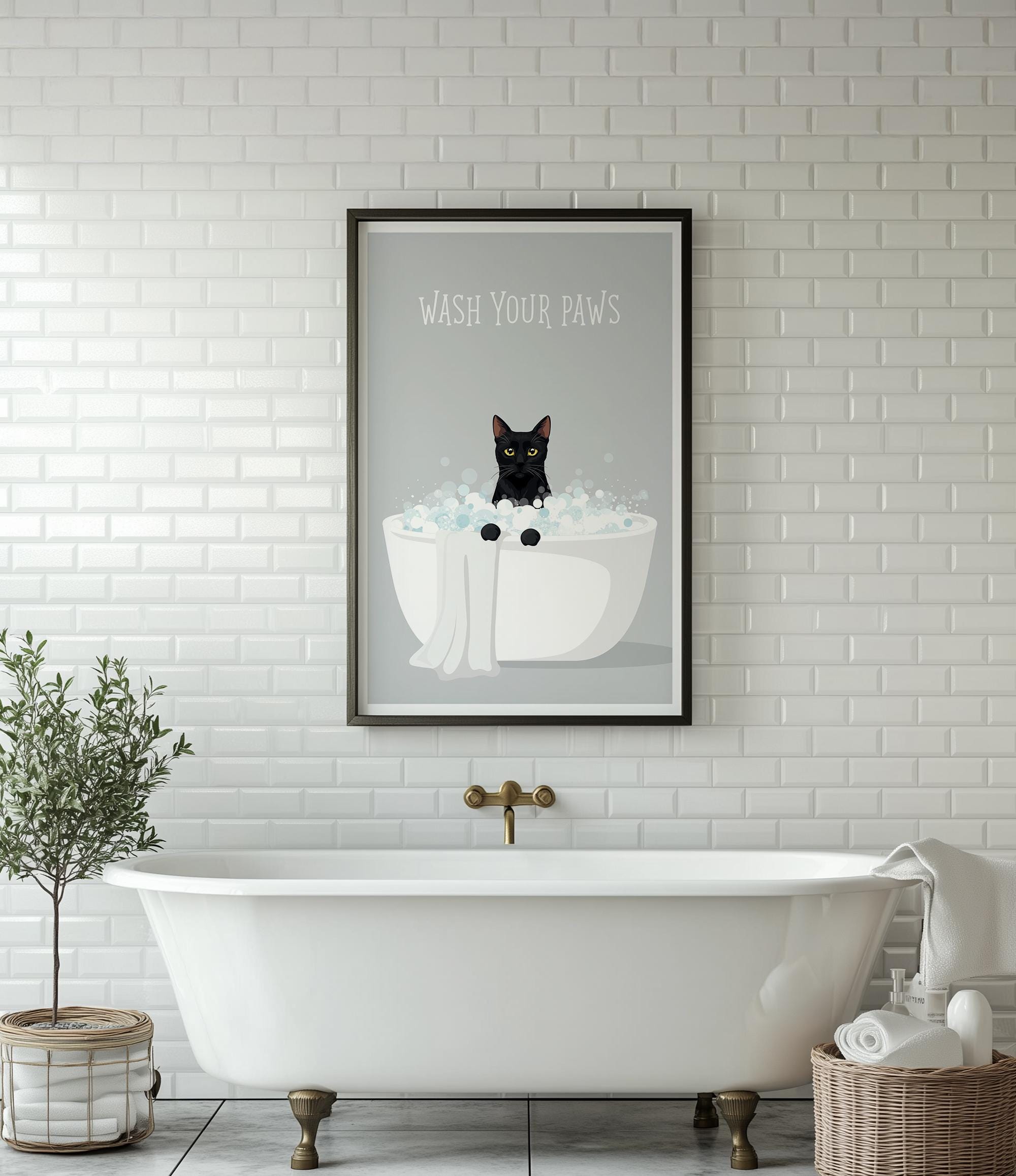 A framed poster with a black cat sitting in a white bathtub, surrounded by bubbles, is displayed on a white tiled wall above a white freestanding bathtub.