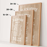 three framed beach house rules posters, each with a different size and orientation, displayed on a white wall.