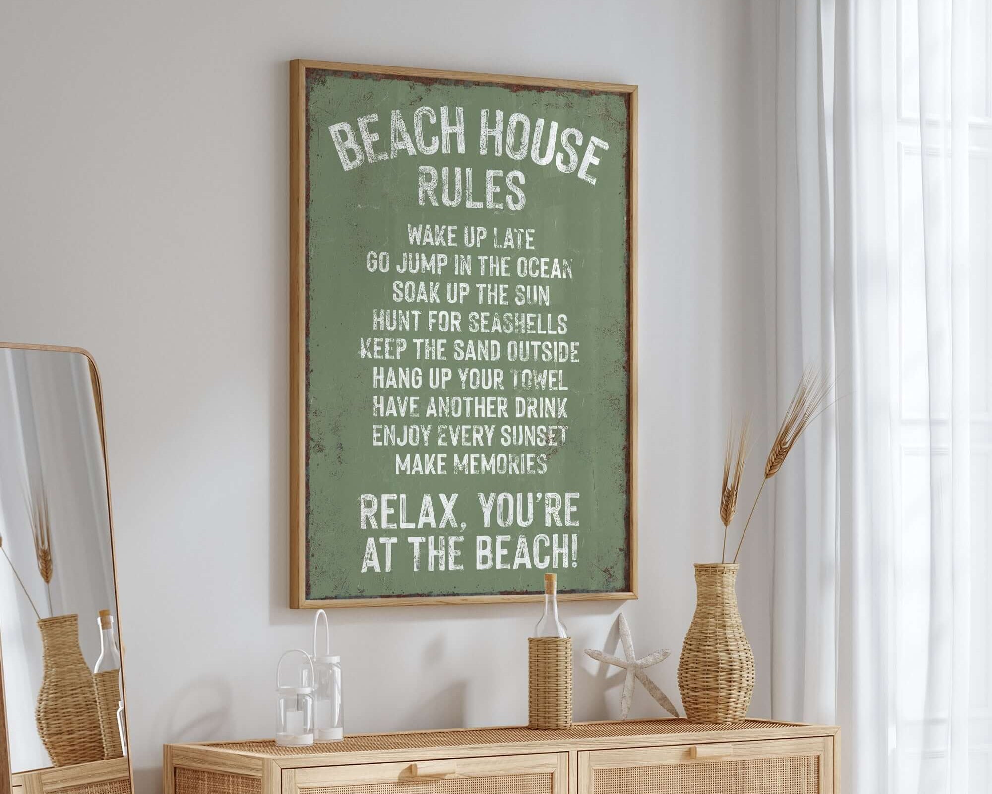 A wooden dresser with vintage decor sits below a framed Beach House Rules Sign, Rusted Edge, Seagrass in a bright, airy room.