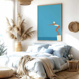 a serene and modern bedroom with a large bed, a potted plant, and a framed artwork of a woman diving into the water.