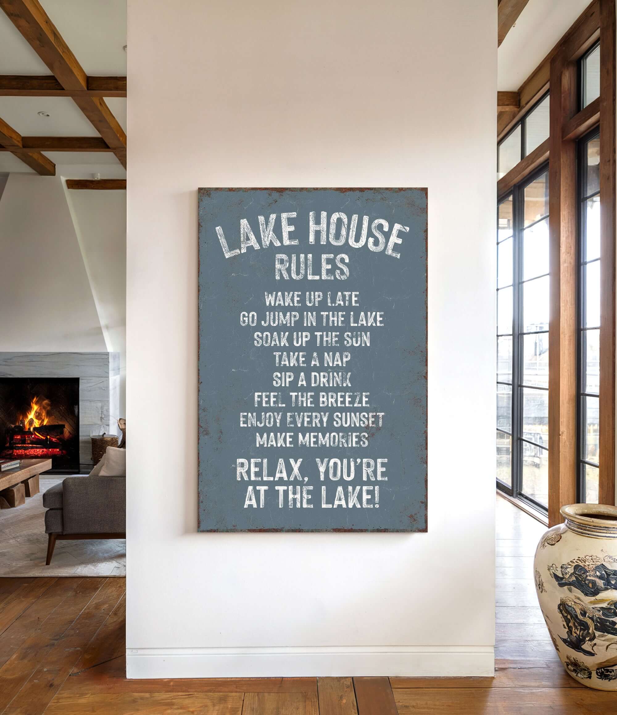 a sign that reads "LAKESHOUSE RULES" hanging on a wall in a room with a fireplace and a vase.