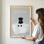 A framed poster with a black dog sitting in a bathtub filled with bubbles, accompanied by the text "WASH YOUR PAWS".