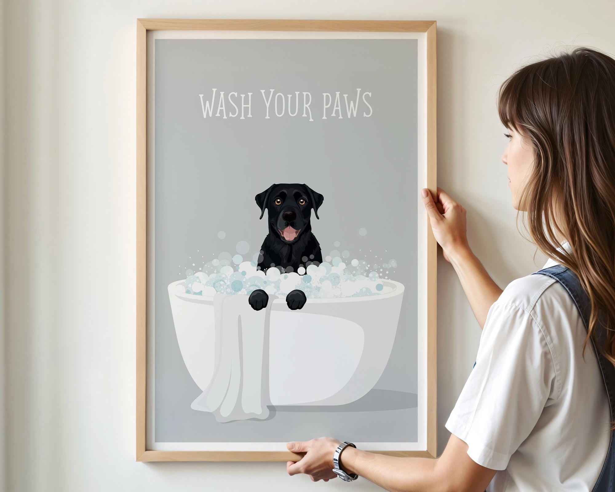 A framed poster with a black dog sitting in a bathtub filled with bubbles, accompanied by the text "WASH YOUR PAWS".