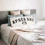a bed with a white sheet and a sign that says "APRÈS SKI" in the center.