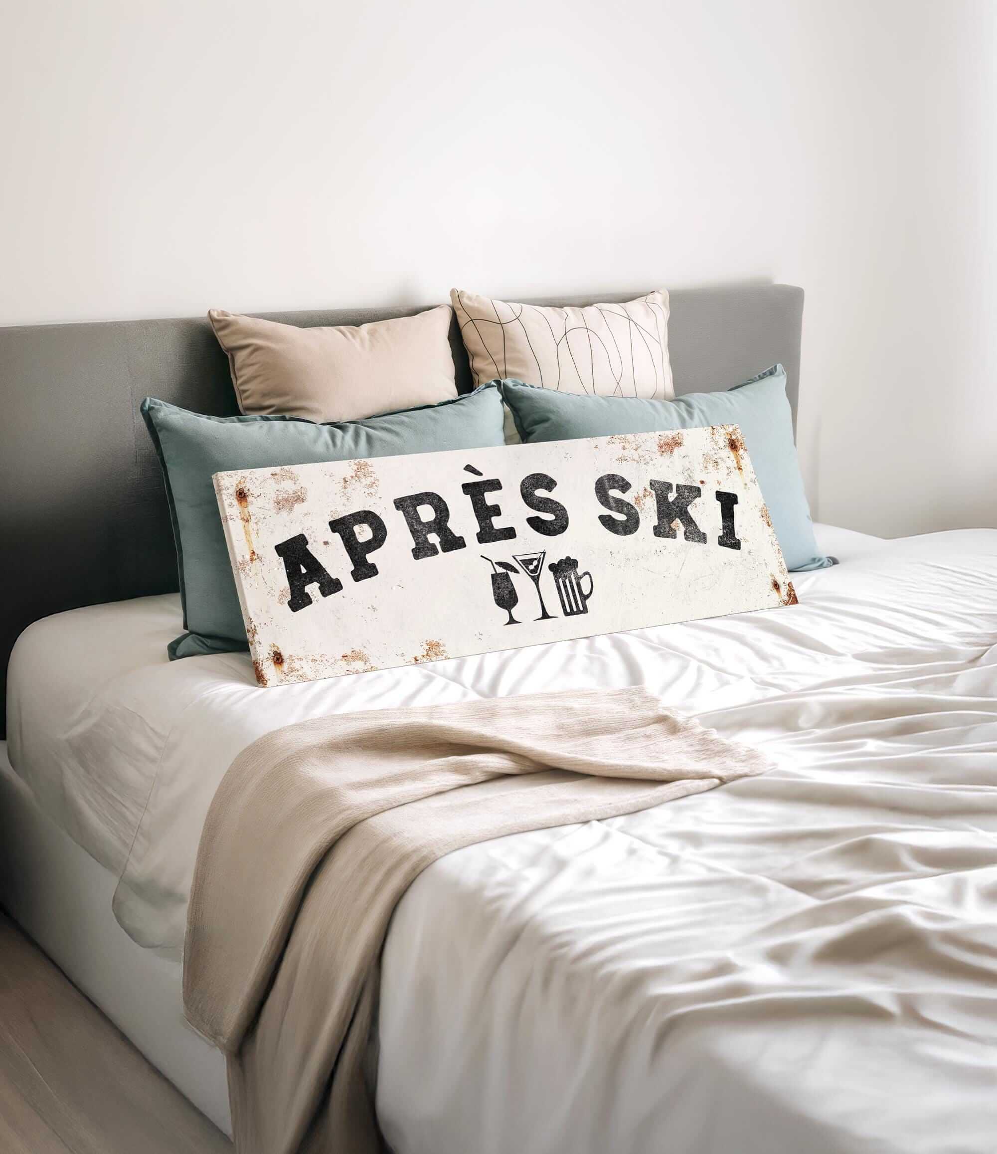 a bed with a white sheet and a sign that says "APRÈS SKI" in the center.