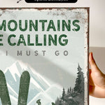 a hand holding a sign that says mountains are calling