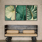 a wooden bench with two beige cushions, positioned in front of three framed botanical prints on a wall.