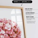 a framed print of a bouquet of pink flowers, with a natural frame.