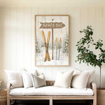 a cozy living room with a large framed picture of skis hanging on the wall above a white sofa with pillows.