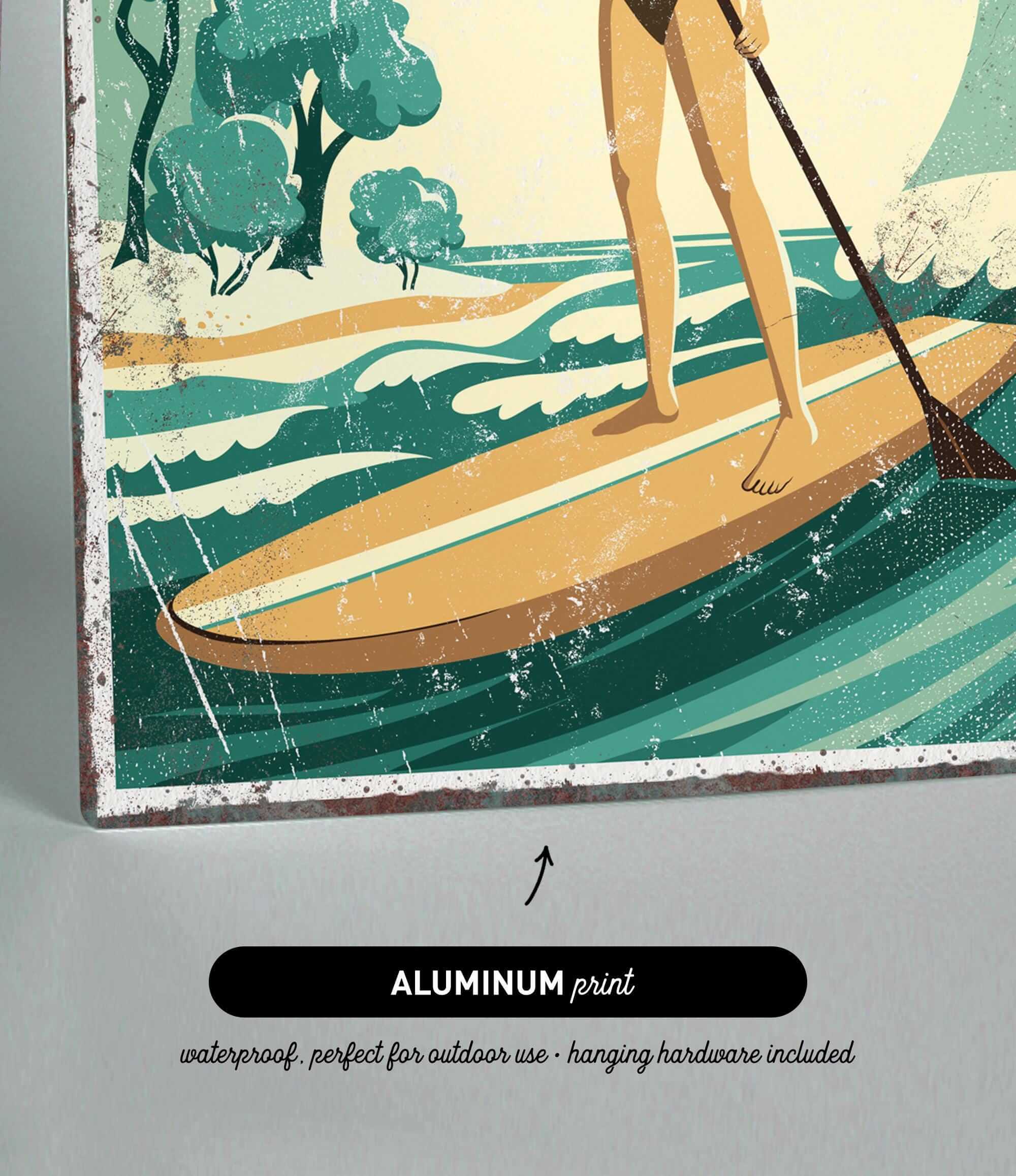 A woman is standing on a surfboard and paddling through the waves, with a beach and trees in the background.