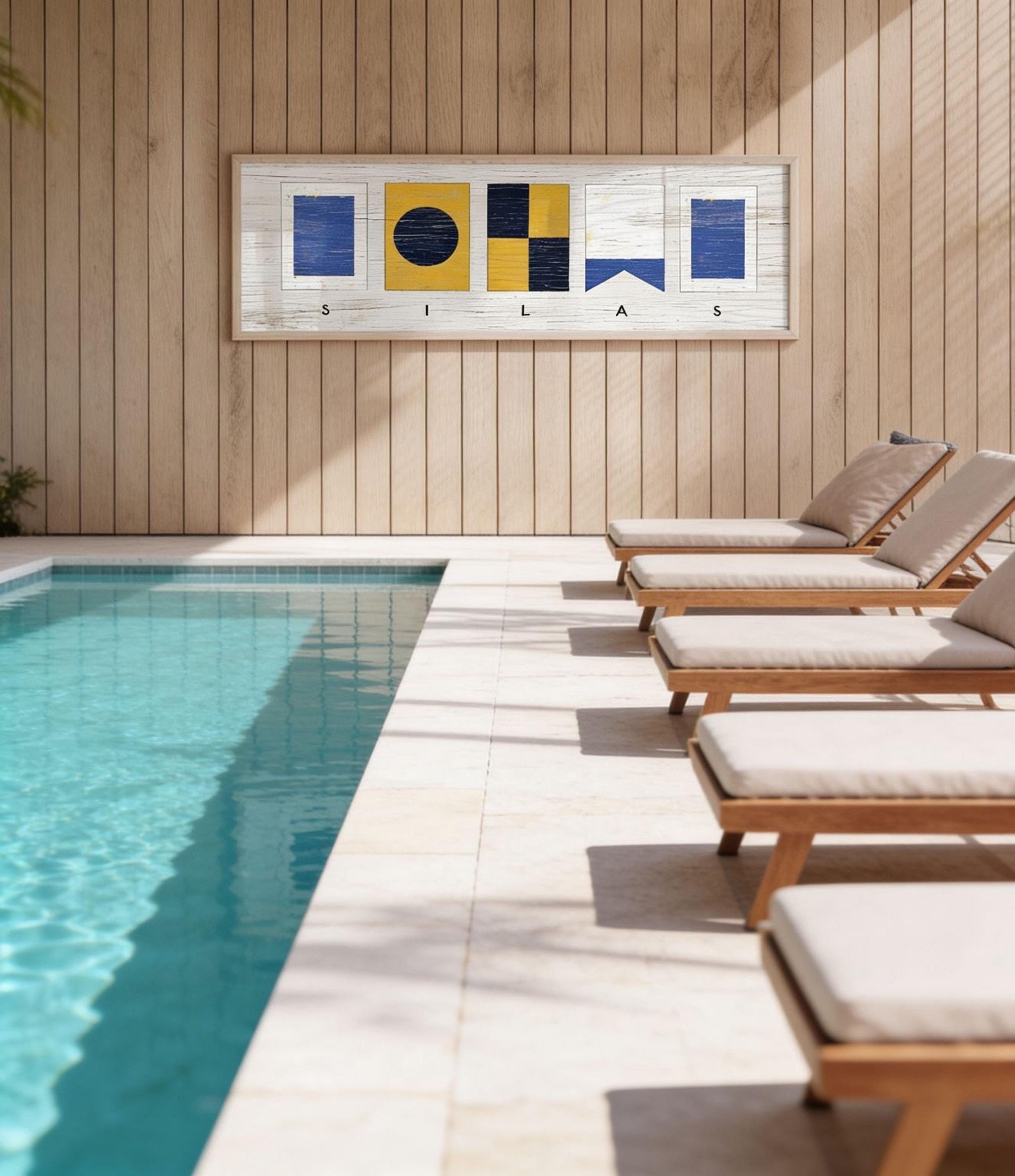 a serene outdoor setting with a swimming pool, wooden lounge chairs, and a wooden wall with a framed artwork depicting nautical symbols.