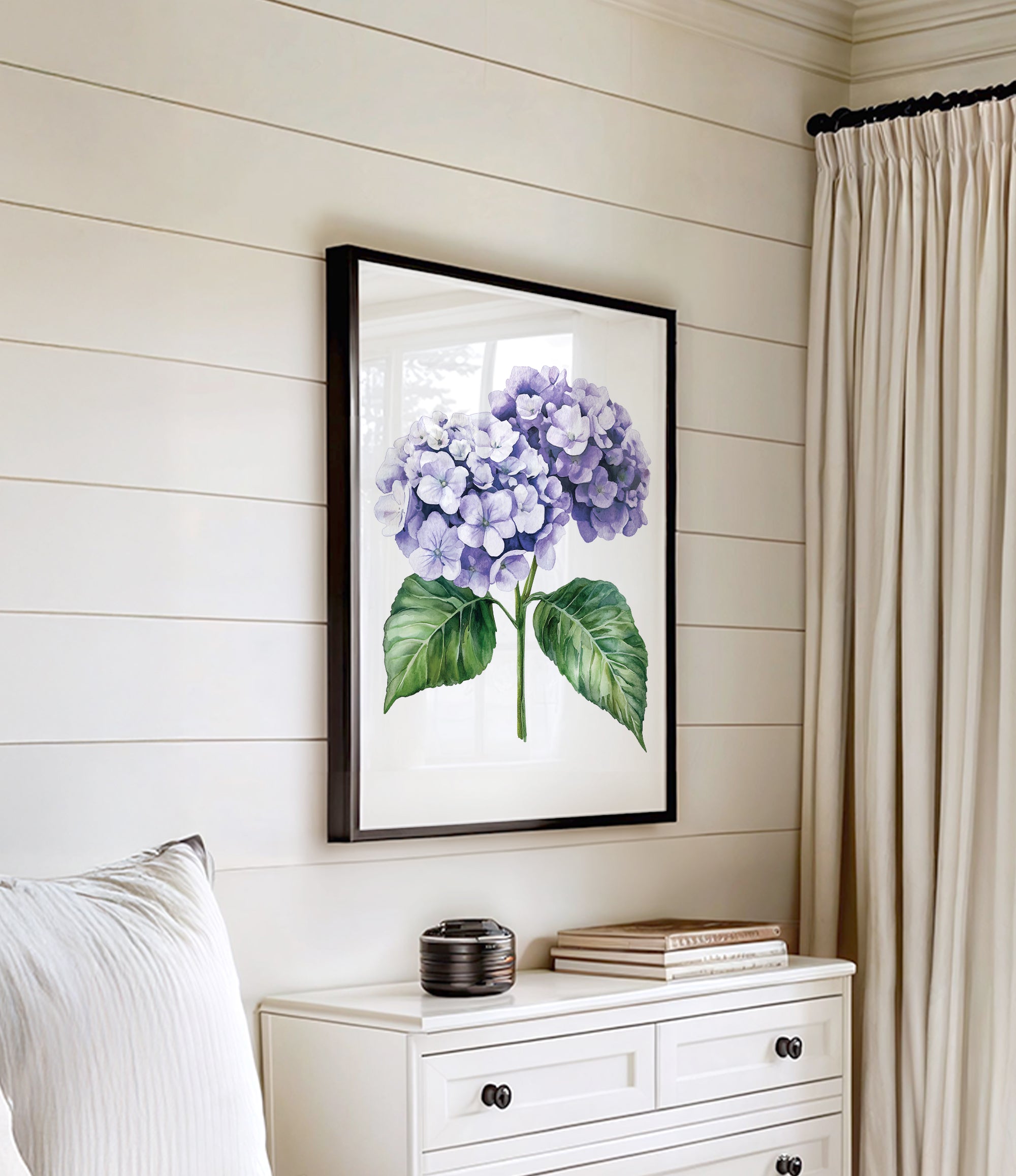 a framed painting of purple hydrangeas hanging on a white wall above a white dresser with a stack of books on top.