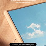 a close-up view of a wooden frame surrounding a canvas print of a blue sky with clouds.
