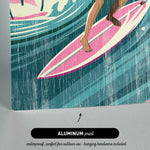 The image is an aluminum print featuring a woman surfing on a pink surfboard.