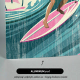 The image is an aluminum print featuring a woman surfing on a pink surfboard.