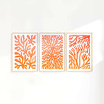 three orange and white paintings on a white wall