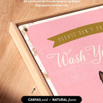 a pink canvas with the text "Please don't forget to wash your hands" written on it. The canvas is framed in a natural frame, and there is a small arrow pointing to the bottom right corner of the canvas.