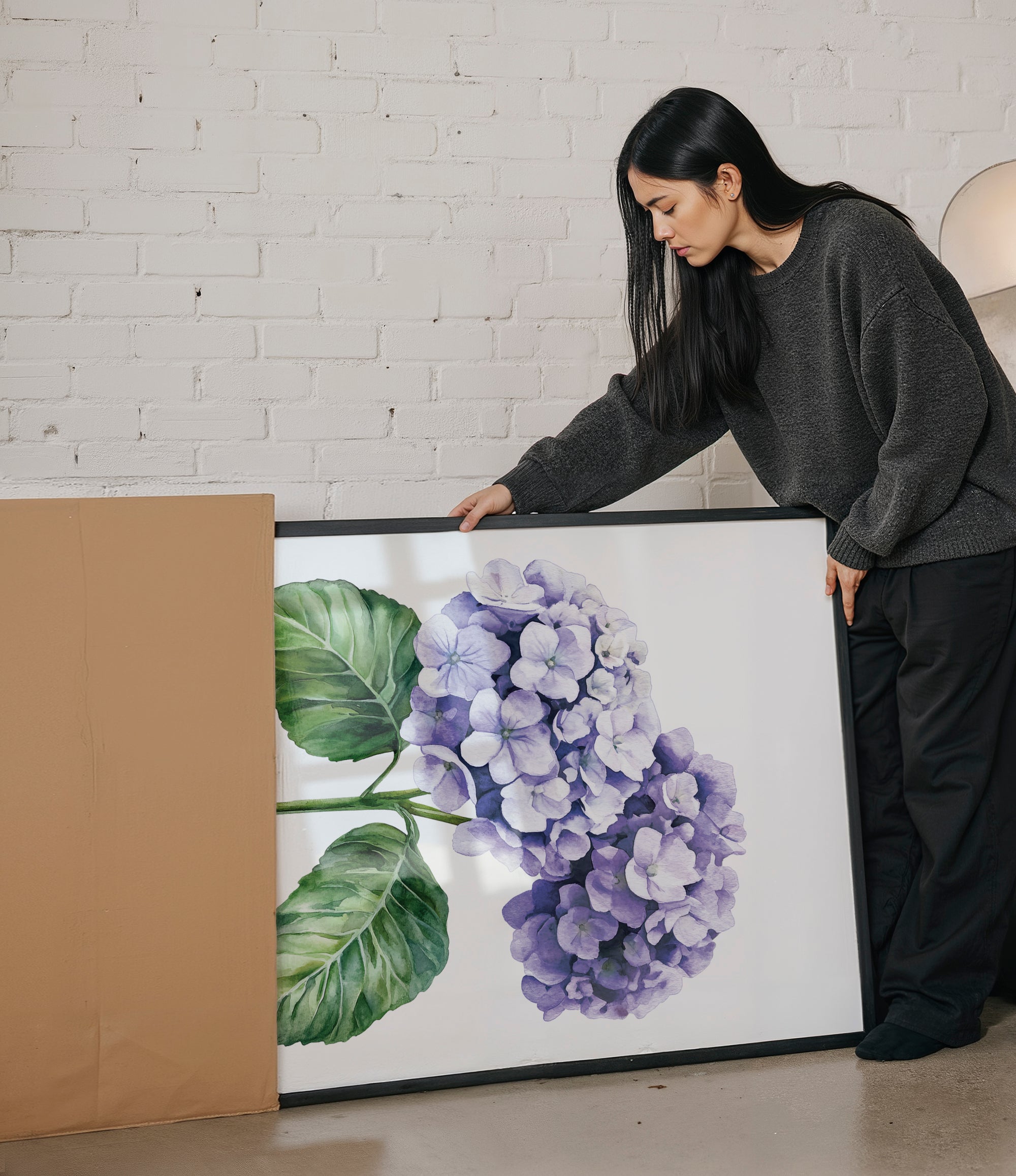 A woman is standing next to a large framed painting of purple hydrangeas, examining the artwork.