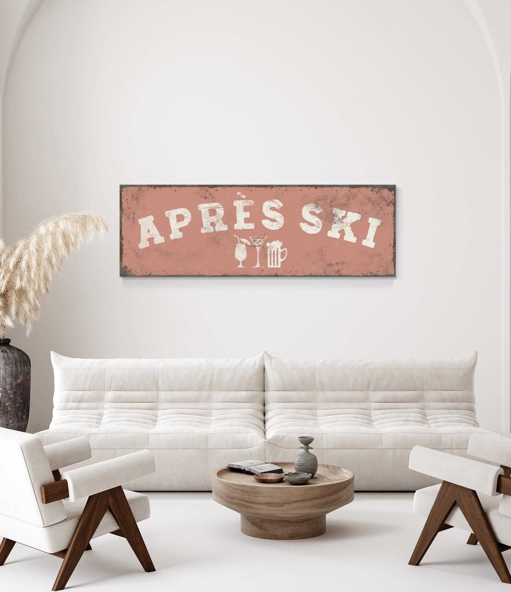 a living room with a white sofa, a wooden coffee table, and a decorative plant. Above the sofa, there is a large sign that says "APRES SKI".