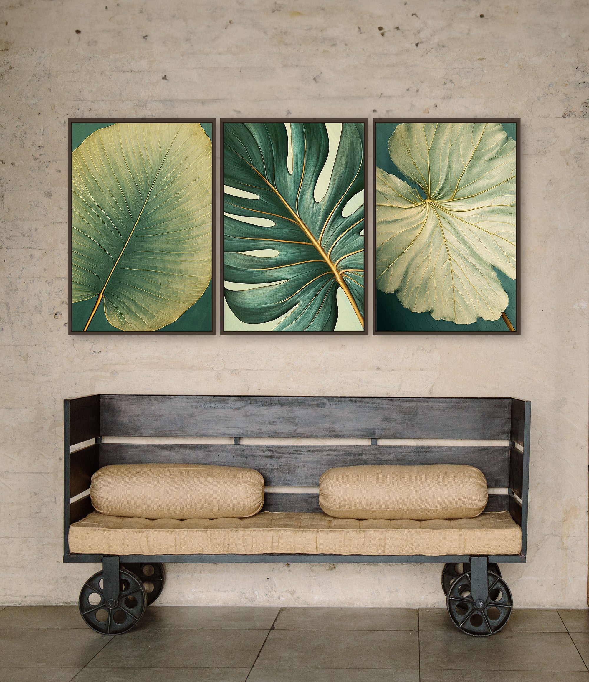 a wooden bench with two cushions, positioned in front of three framed prints of tropical leaves hanging on a wall above it.
