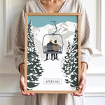 A person is holding a framed picture of a couple on a ski lift, surrounded by snow-covered trees, with the word "APRÈS" visible.