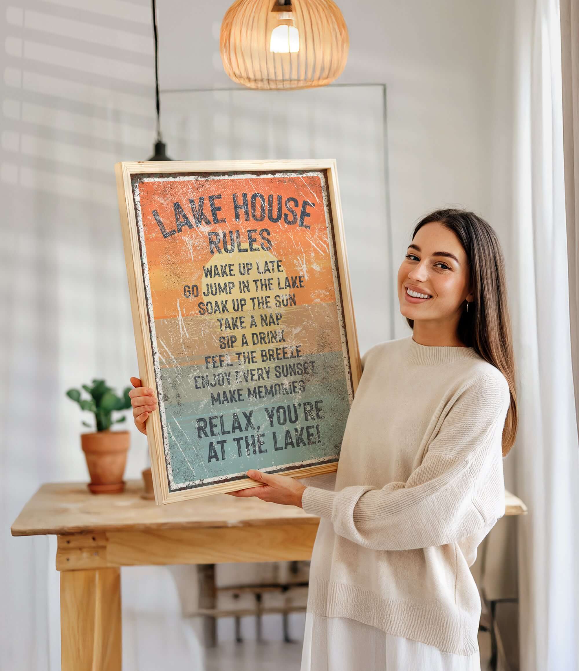 A woman is holding up a framed sign with a list of rules for a lake house, smiling and posing for the camera.